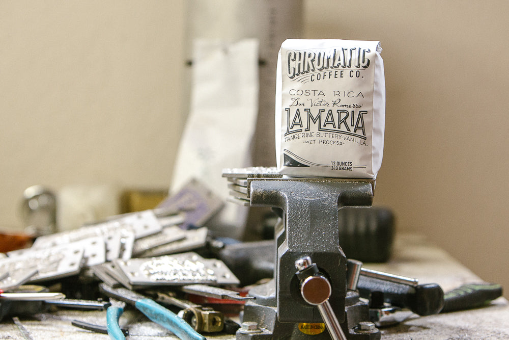 A retail bag of coffee on a vice grip in a workshop