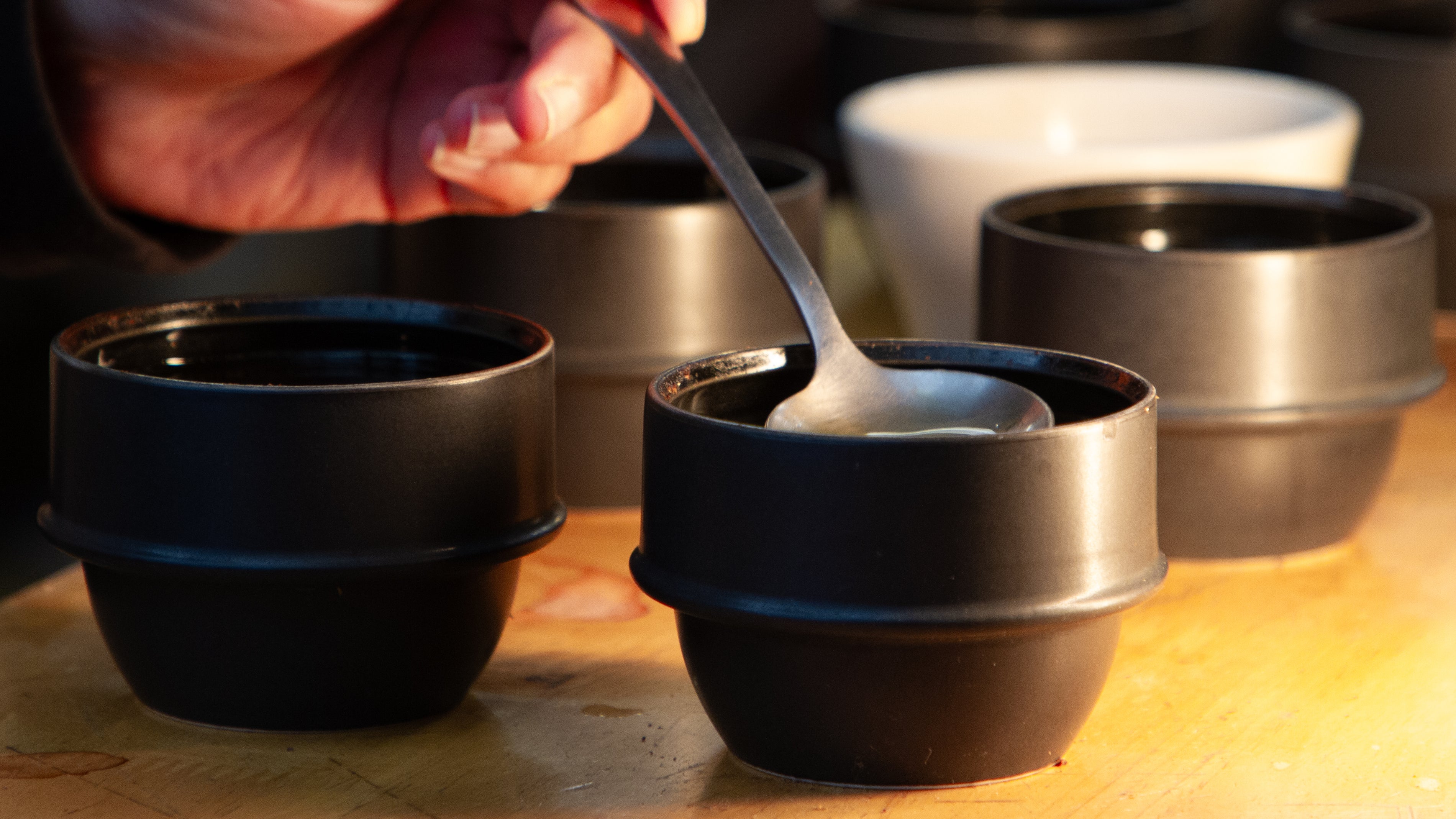 A hand cupping coffee under warm lighting on a wooden surface