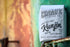 A pack of Chronic Coffee Co. Papua New Guinea Kunjin coffee, with branding and product information, placed on a rusted metal surface against a colorful wall.