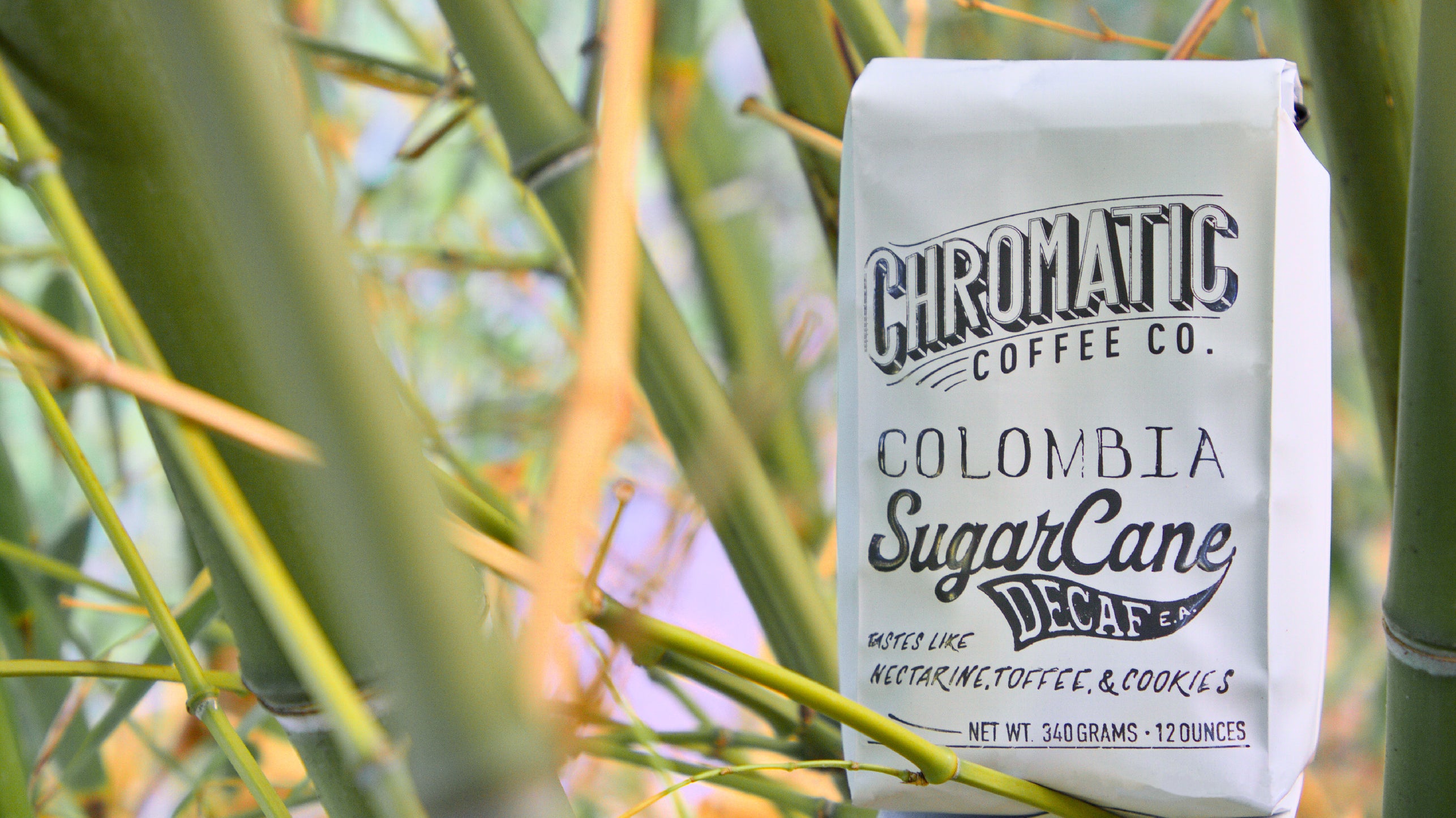 Sugarcane Decaf-Chromatic Coffee-Bag of Chromatic Coffee Colombia SugarCane Decaf among green bamboo stalks.