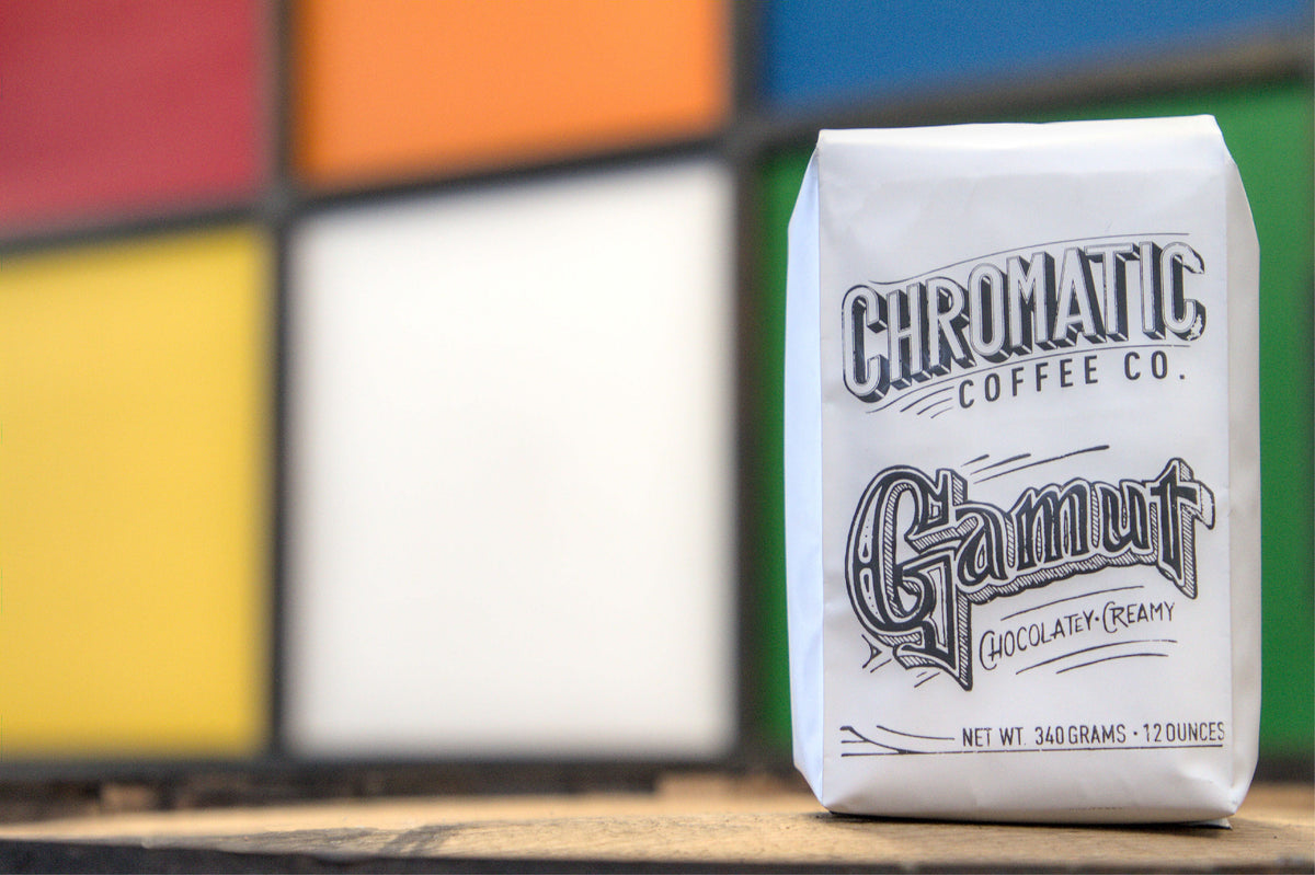 A bag of Chromatic Coffee Co. Gamut coffee placed in front of a colorful background.