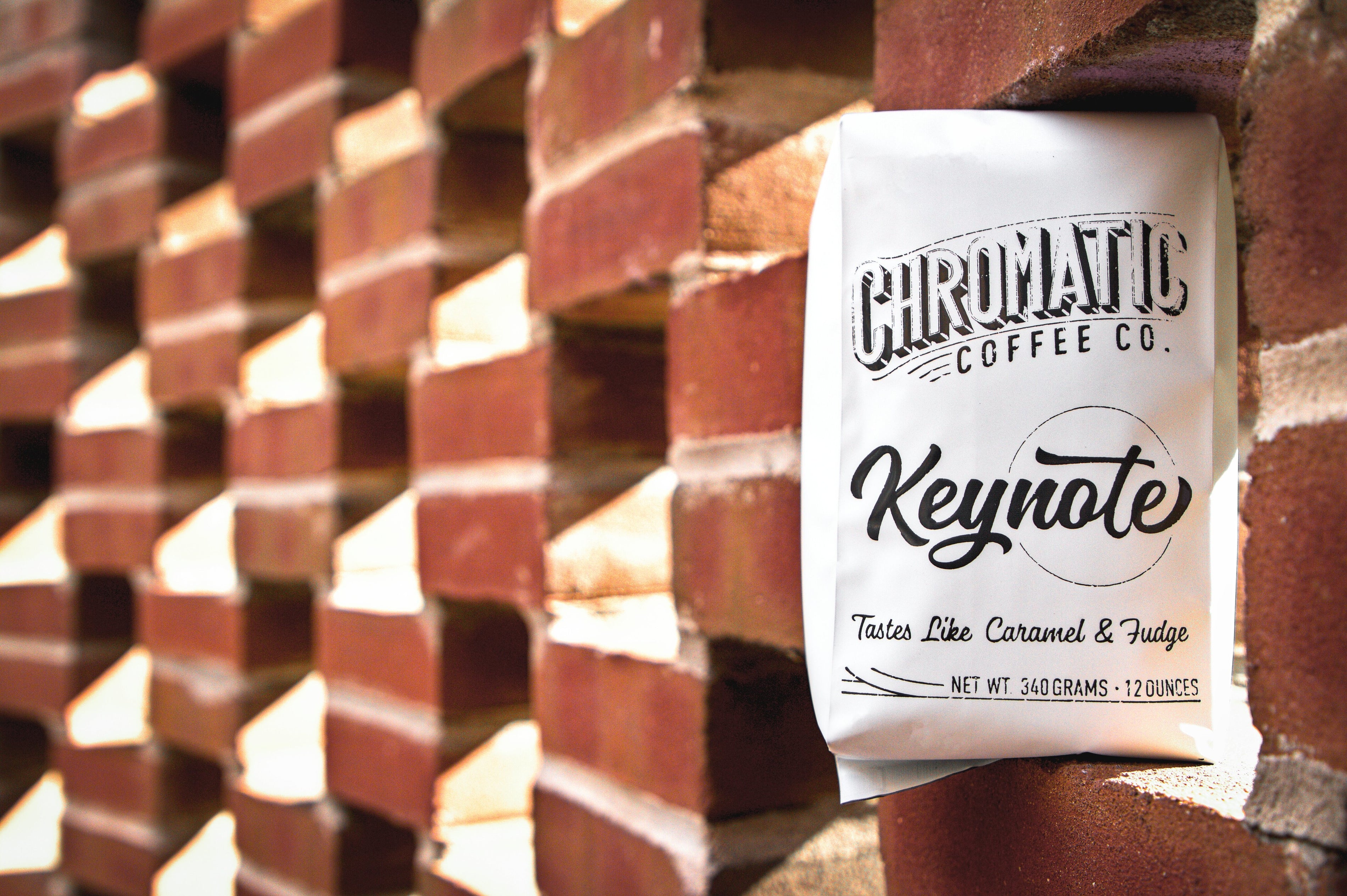 A pack of Chromatic Coffee Co. Keynote coffee, with the brand name and product description visible, placed against a brick wall background.